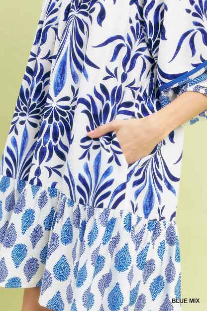 Marina Blue Mix Babydoll Dress in white with blue floral patterns, puff sleeves, ruffled hem, and pockets. Available in sizes XS–XL.
