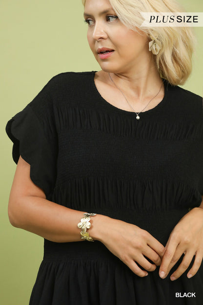 The Amelia Smocked Peplum Top in black linen blend with ruffle details, available in plus sizes.