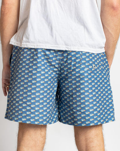 Men’s On The Fly Swim Trunks in blue with repeating fish pattern. Sizes available: S-XXL.