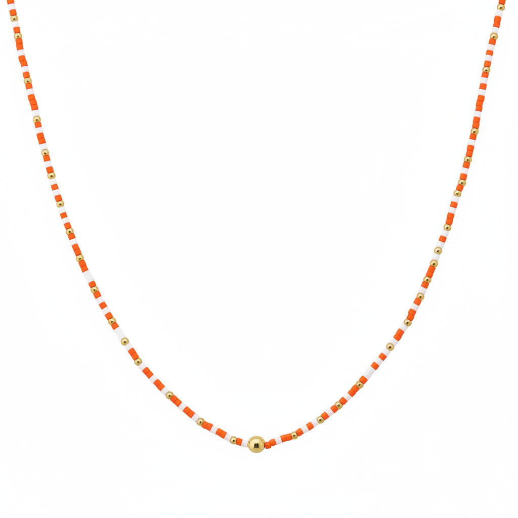 The Cleo Orange White Beaded Necklace features alternating small orange and gold beads with a larger gold bead at the center. Available in multiple sizes.