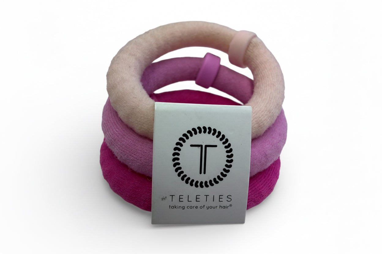 Set of three pink velvet Teleties hair ties with silver “TELETIES taking care of your hair” tag; available in multiple sizes.