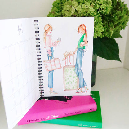 Open spiral-bound 2025 Planner with an illustrated cover; available in small, medium, and large sizes.