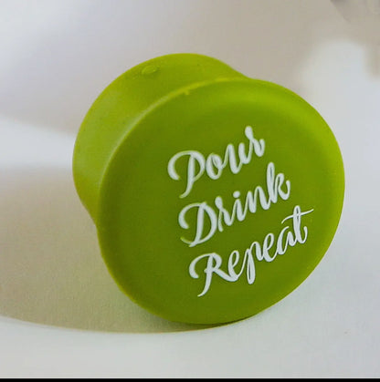 Green cap reads "Pour Drink Repeat" in white cursive; reseals wine bottles. Available in standard and large sizes.