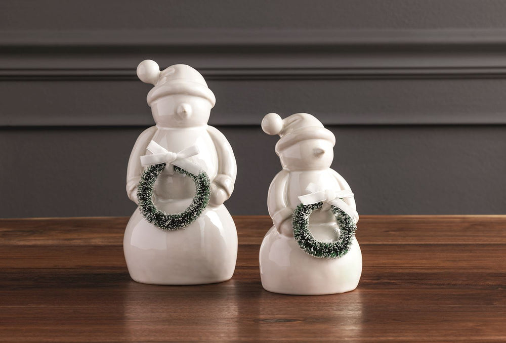 Glossy white ceramic snowman figures wearing hats and holding green wreaths.