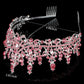 Silver tiaras with pink gemstones, intricate details, and hanging gems. Size: 4.92" wide x 2.83" tall.