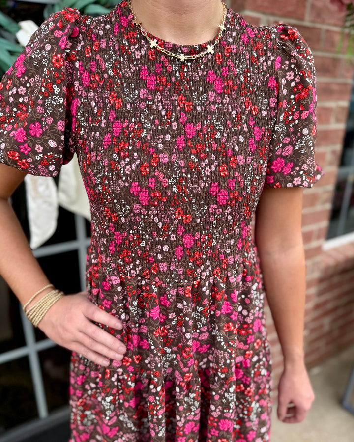Lucille Granada Glen Cocoa Dress: cocoa brown maxi dress with red, pink, and white floral patterns, smocked bodice. Available in sizes XS-XL.