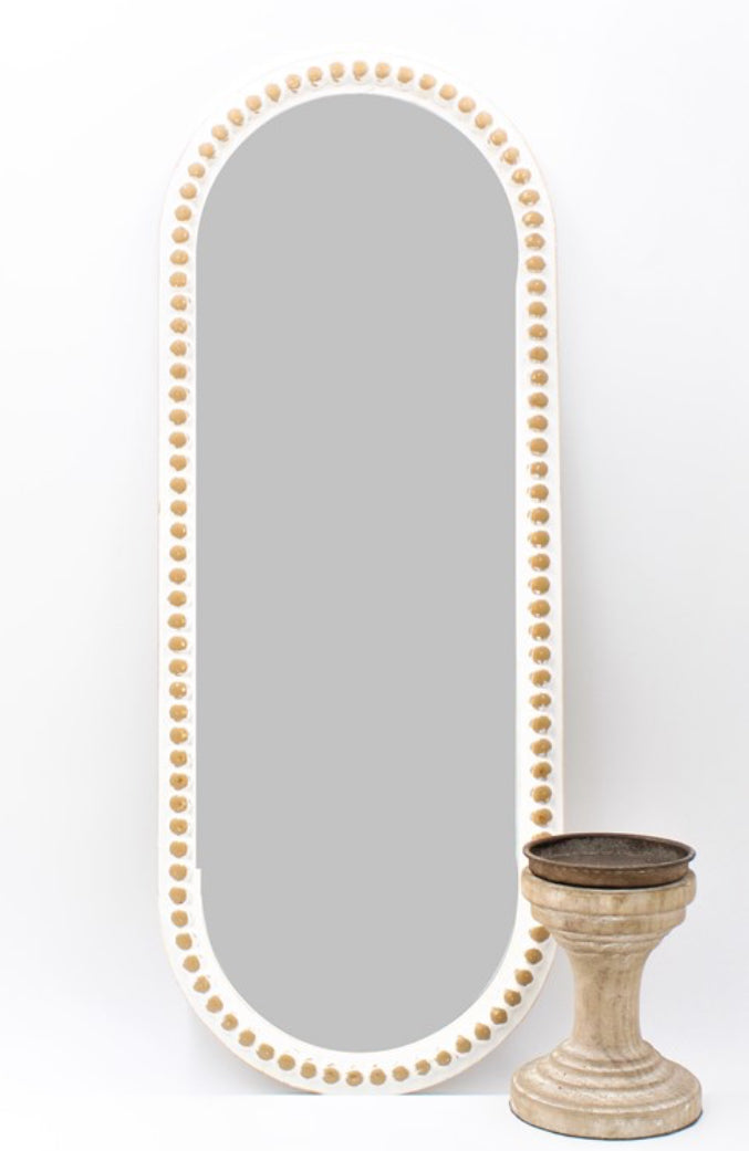 The product is a 9 x 24 Oval Beaded Mirror. This mirror features a decorative frame adorned with pearl-like beads. The mirror is designed to be positioned vertically.