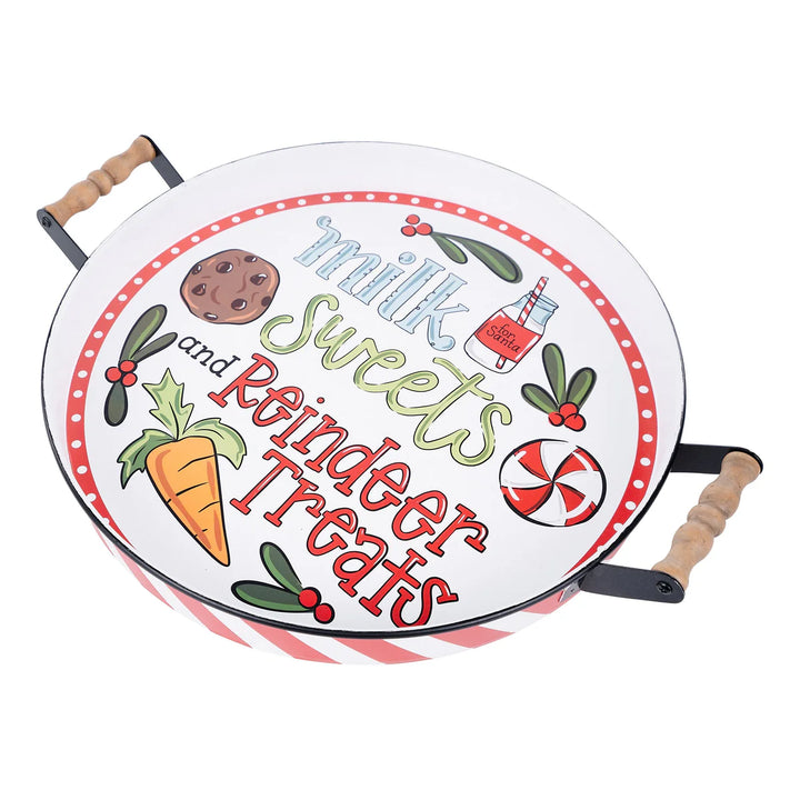 Milk Sweets &amp; Reindeer Treats Enamel Tray: a round white enamel tray with wood-handled metal sides featuring a holiday design with a cookie, a carrot, a milk jar, and the text “Milk Sweets and Reindeer Treats.”.