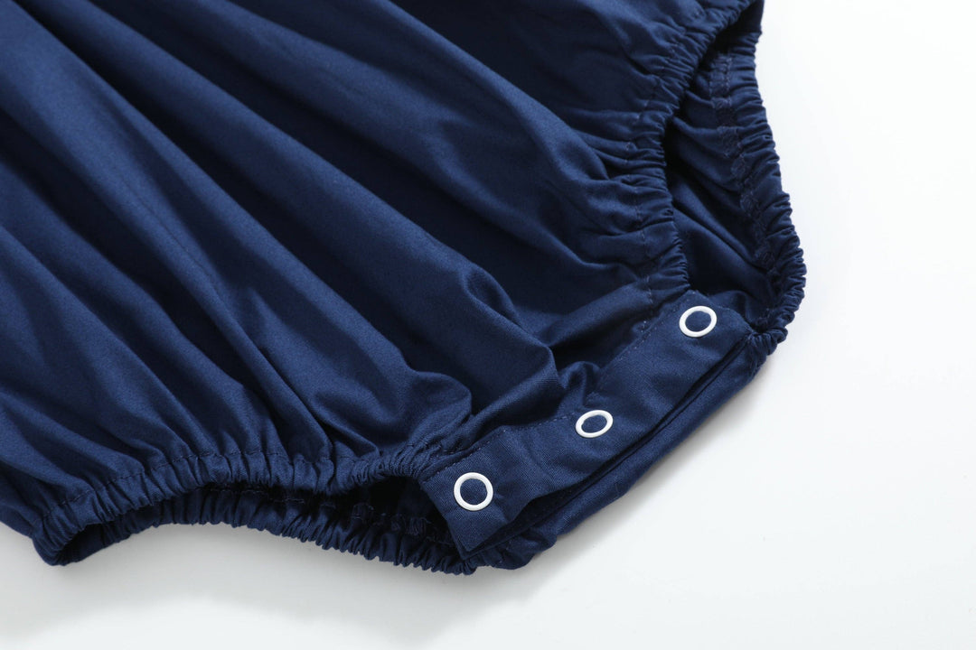 Navy blue Blue Nativity Smocked Ruffle Romper, size 3-6M, with elastic leg openings and three metal snap buttons on the bottom.