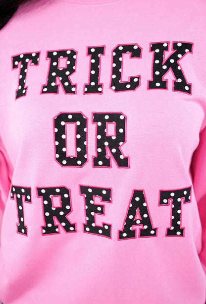 Trick or Treat Polka Dot Pullover in pink with “TRICK OR TREAT” in bold black letters, white polka dots, and pink outline. Available in sizes S–XL.