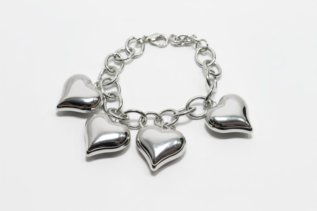 Silver chain bracelet with four evenly spaced metallic heart charms. Available in sizes S, M, and L.