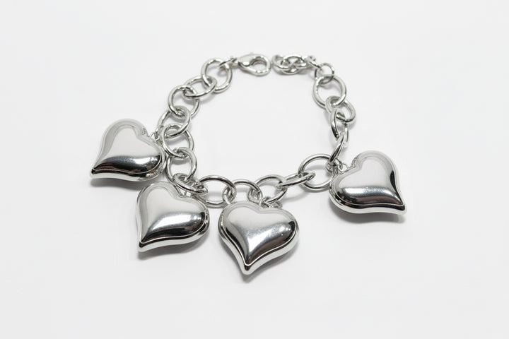 Silver chain bracelet with four evenly spaced metallic heart charms. Available in sizes S, M, and L.