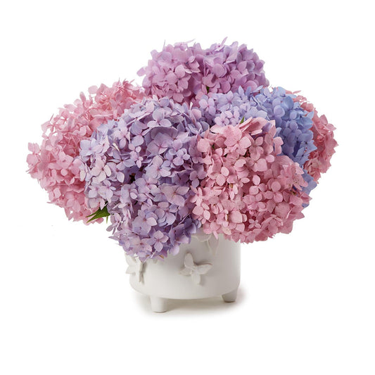 Butterfly Footed Cachepot with sculpted butterflies, shown holding hydrangeas. Available in small and large sizes.
