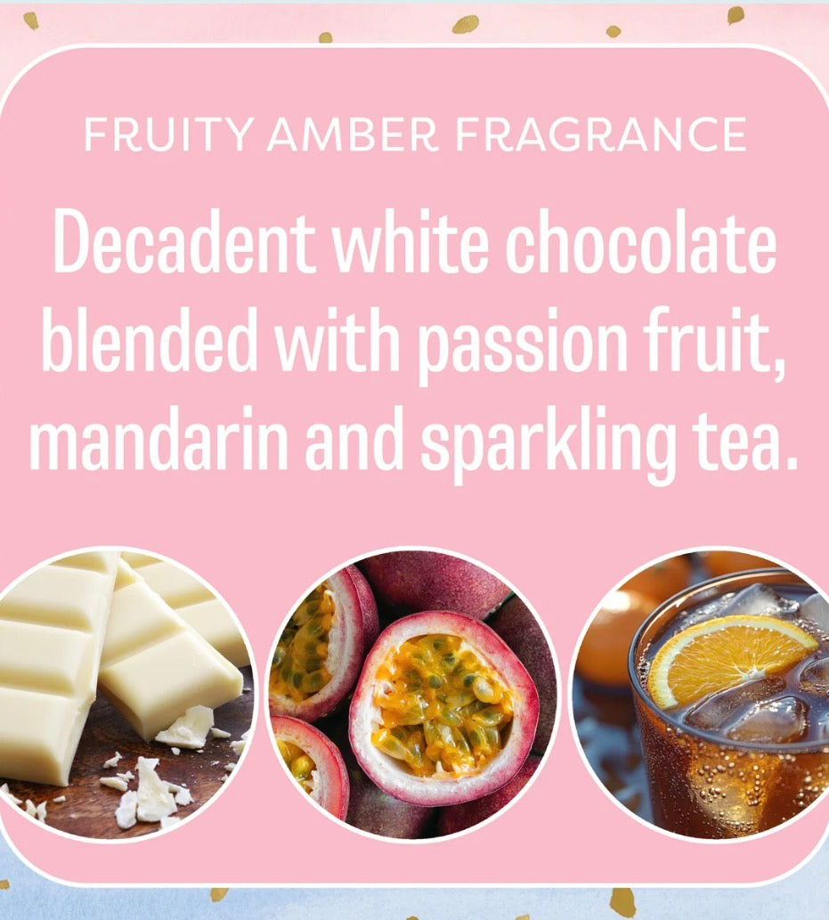 Little Sparkle Scented Sachet features a pink label describing its fragrance as white chocolate, passion fruit, mandarin, and sparkling tea, with corresponding images on the packaging. Available in multiple sizes.