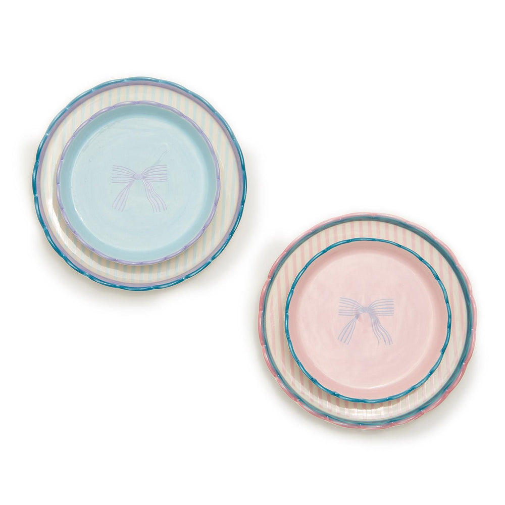 Two sets of trinket dishes made from durable stoneware. Each set includes three plates: one blue with stripes and a bow design, and the other pink, both featuring pastel artisanal looks. Available sizes: Small, Medium.