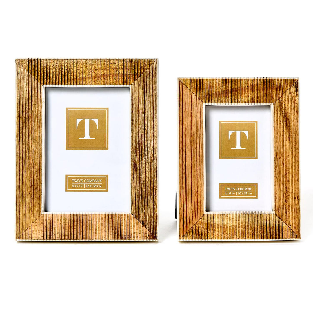 The Striated Textured Frames are crafted from mango wood, featuring a simple design with a "T" on a golden square against clear, white backgrounds. Sizes: Larger frame and smaller frame.