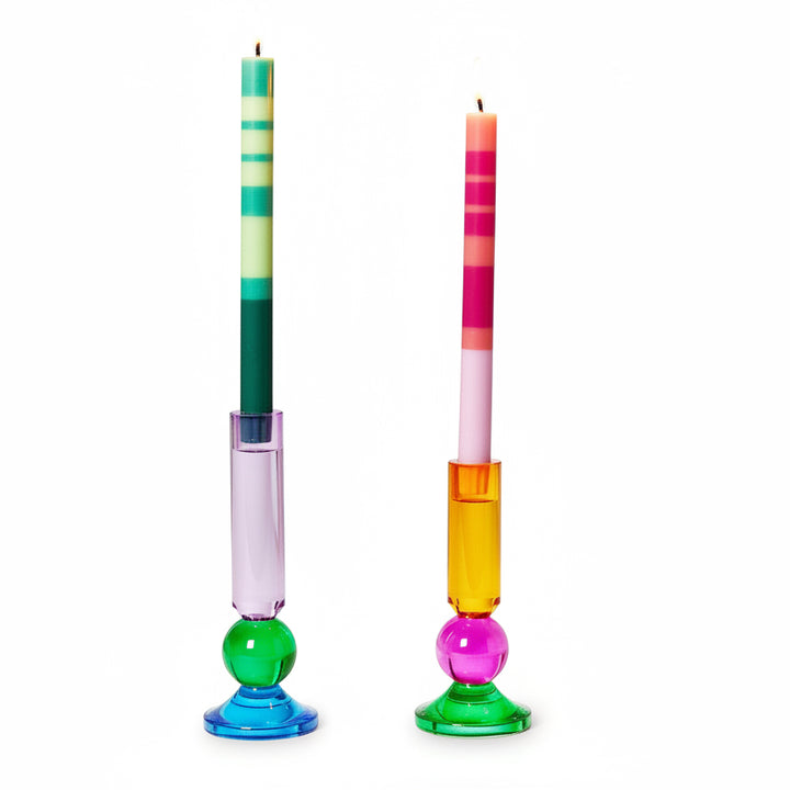 Two vibrant striped candles, one green-blue, one pink-orange; available in standard taper size.