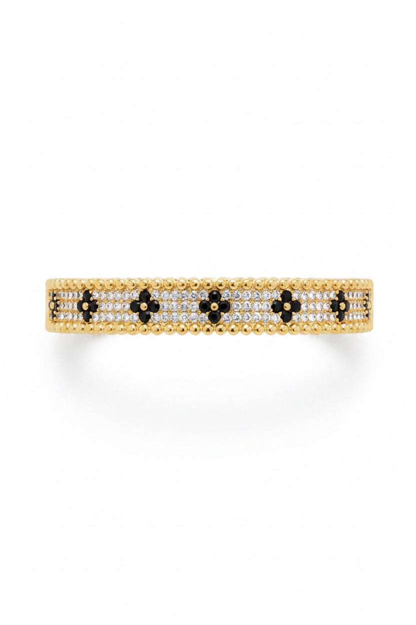 Gold bangle with white and black stones in a floral pattern, bordered by gold beads. Available sizes: S, M, L.