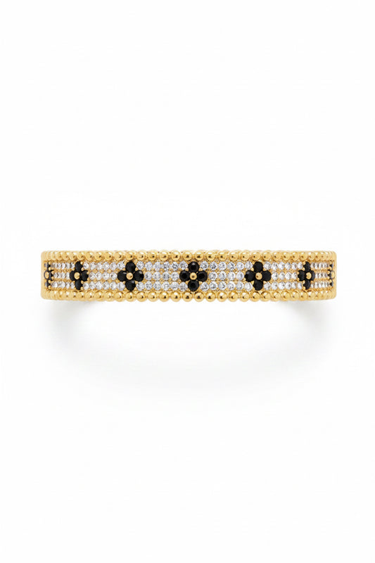 Gold bangle with white and black stones in a floral pattern, bordered by gold beads. Available sizes: S, M, L.