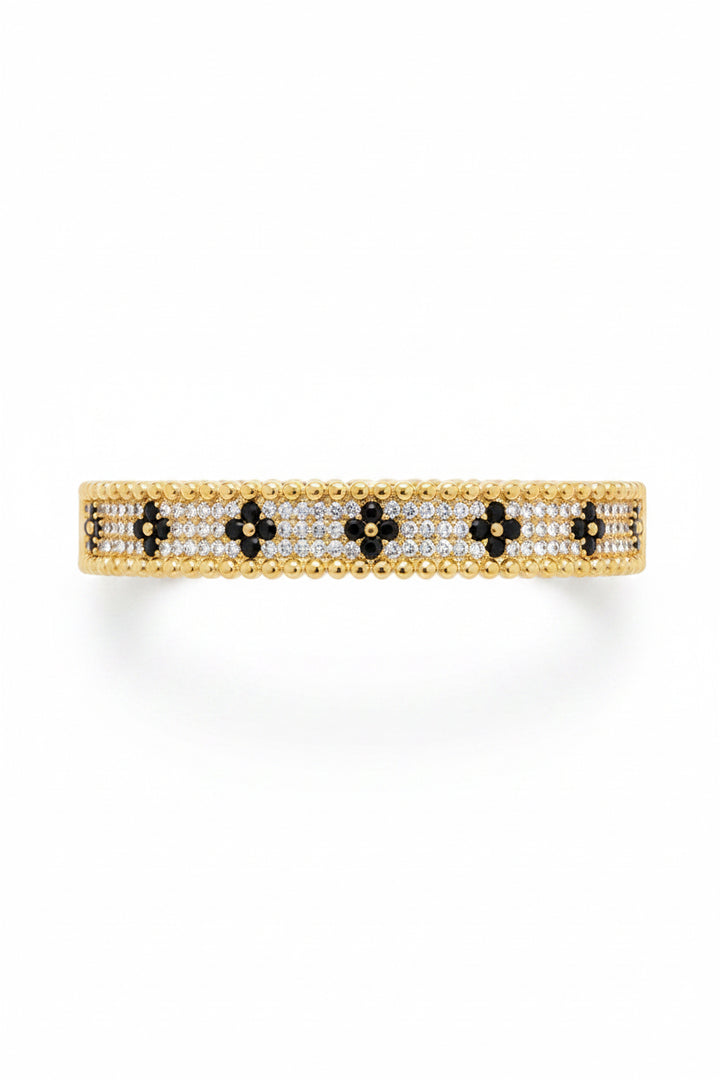 Gold bangle with white and black stones in a floral pattern, bordered by gold beads. Available sizes: S, M, L.