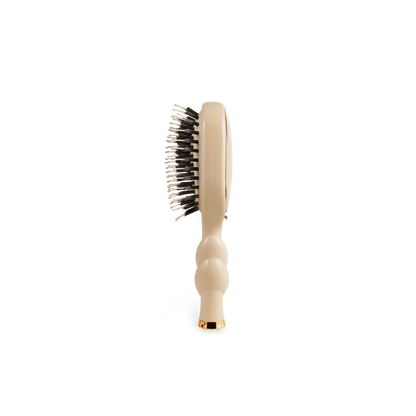 The Mini Boar Brush | Tan has a contoured handle with black and white bristles. Available in mini size.