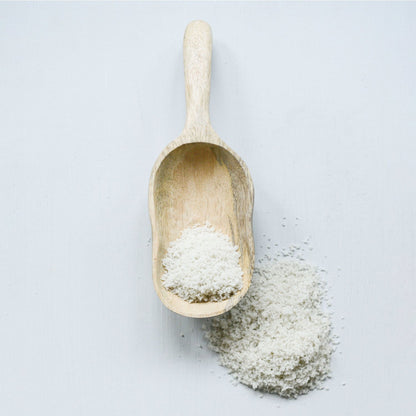 Hand carved mango wood scoop filled with powder. Available in small, medium, and large sizes.