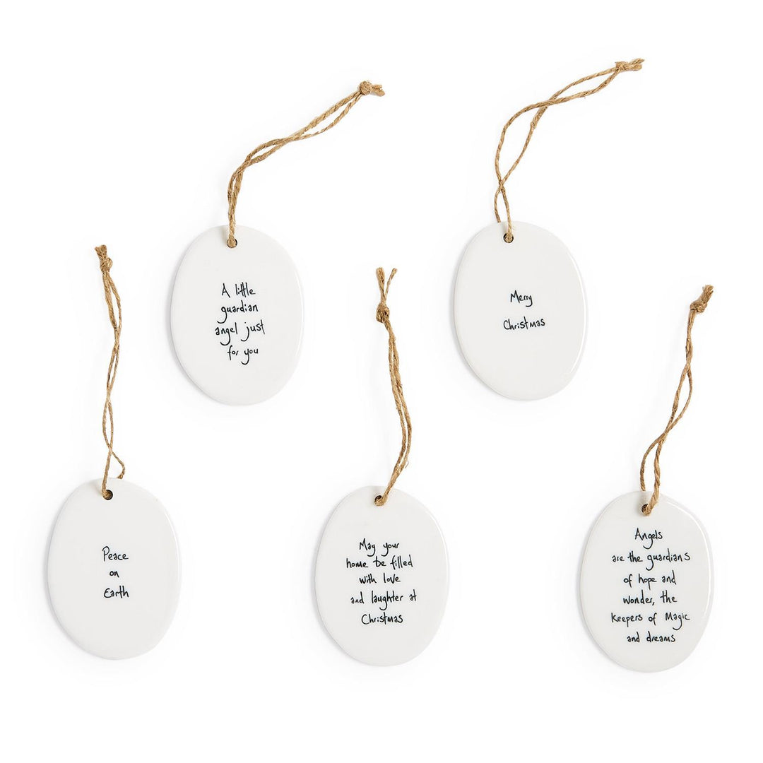 Five oval porcelain ornaments with blue and white handcrafted Christmas messages on twine loops.