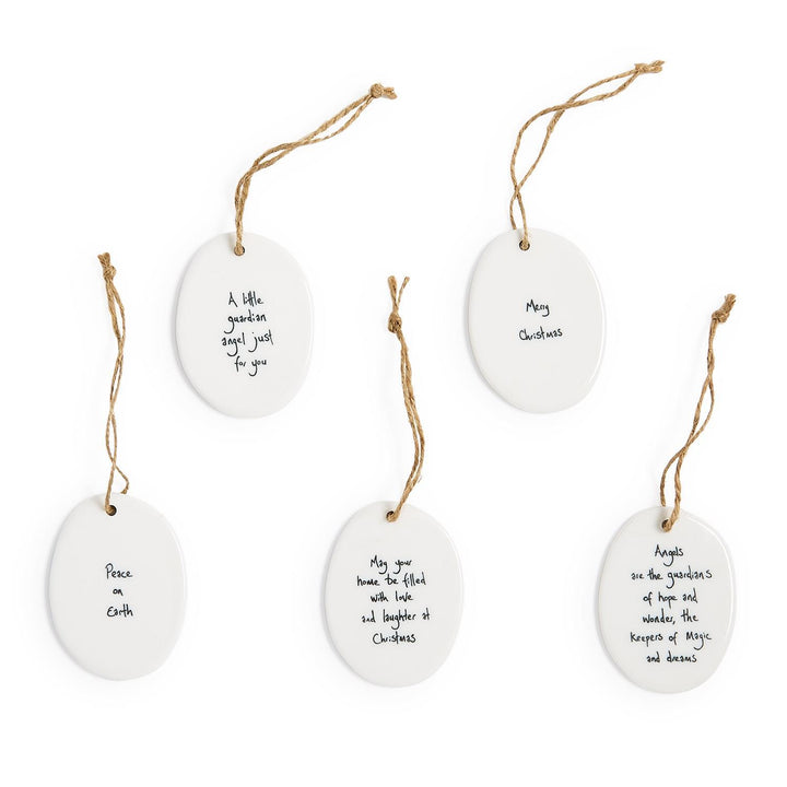 Five oval porcelain ornaments with blue and white handcrafted Christmas messages on twine loops.