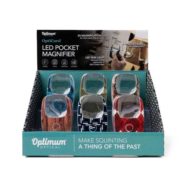 Six Optimum Optical The Hobbyist OptiCard LED Pocket Magnifiers in assorted colors and patterns, each with 2X magnification and a built-in LED light. Sizes available: pocket-sized. Text on packaging: “Make squinting a thing of the past.”.