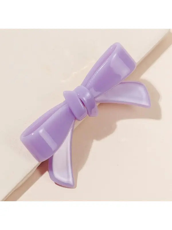 Smooth, shiny, light purple Shiny Bow Acrylic Alligator Hair Clip with a glossy finish and neatly tied loops on a light beige surface. Available Sizes: One Size.