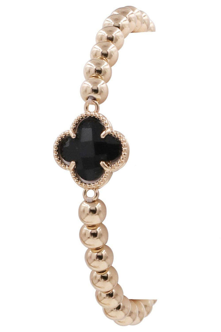 Gold beaded bracelet with a black crystal clover charm framed by textured gold. Available sizes: S, M, L.