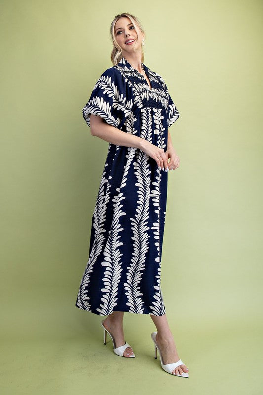 Navy blue midi dress with white fern print, short puff sleeves, and gathered neckline. Sizes available: [Insert sizes].