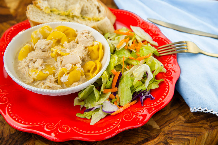 Top Notch Chicken Alfredo Tortellini with shredded chicken on a red plate. Available in small, medium, and large sizes.