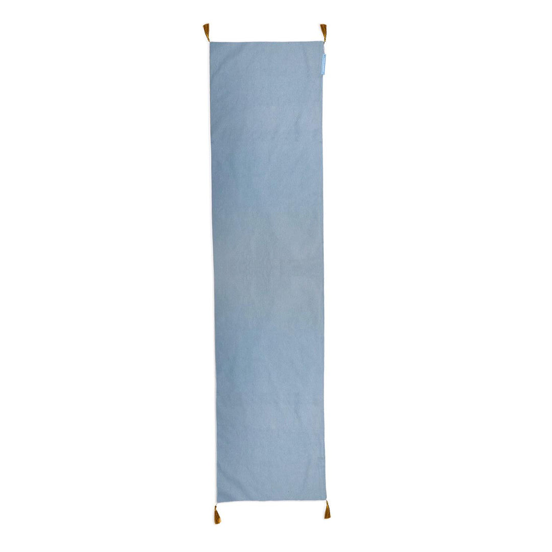 Light blue rectangular Gilded Cottage double-sided table runner with gold corner tassels.
