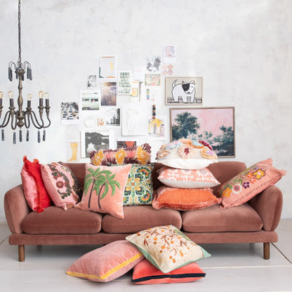 Pink velvet sofa with colorful, embroidered pillows. Available in multiple sizes. Features a Clay 20” square eyelash fringe pillow.