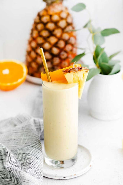 Tall glass of creamy yellow smoothie made with Wine & Cocktail Slush Mix Bags, garnished with pineapple and orange. Available in 8oz and 16oz.