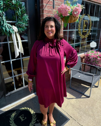 Plum Satin Tie Neck Dress with elegant satin finish and tie-neck detail; available in sizes XS-XL.
