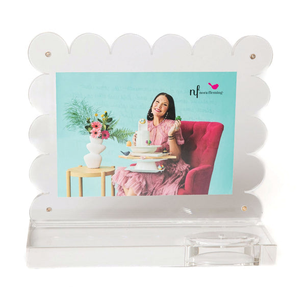 Nora Fleming A-Nora-Able Acrylic Frame with scalloped edge, holder at base; fits 4x6 or 5x7 photos.