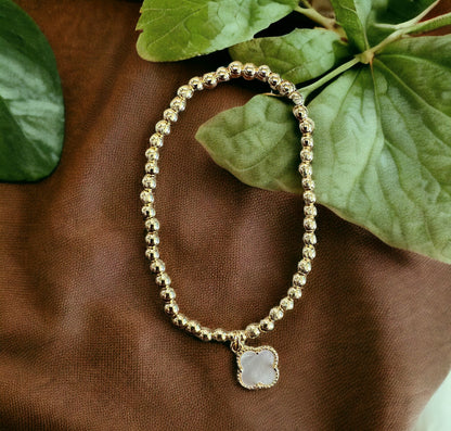 Gold stainless steel beaded bracelet with clover-shaped pale stone charm. Available in sizes S, M, and L.