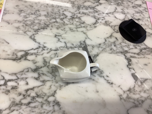 Small white porcelain creamer, available in multiple sizes, with a smooth finish and simple curved shape.