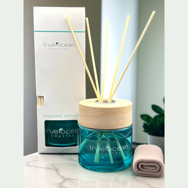The True Ocean Reed Diffuser with blue liquid, wooden cap, and reed sticks, shown with branded box. Available in 100ml, 200ml.