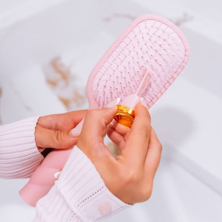Medium bubblegum pink Detangler Brush with integrated gold-capped tool.