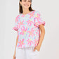 Cassidy Hibiscus Harmony White Top: floral, short sleeves, ruffled cuffs, crew neck. Available in sizes XS–XL.