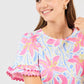 Cassidy Hibiscus Harmony White Top: crew neckline, pink/yellow/blue floral print, short ruffled sleeves. Sizes XS–XL.