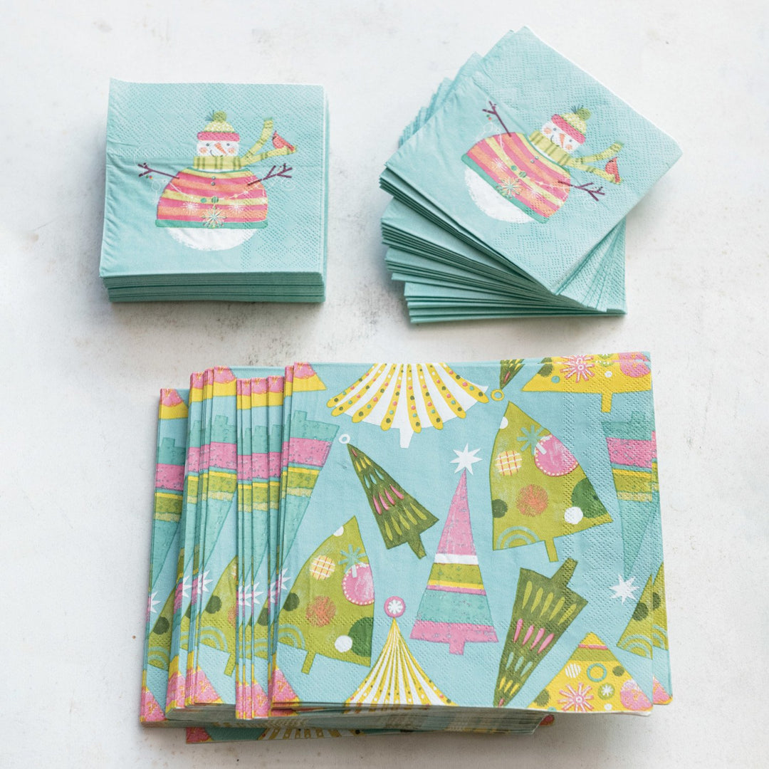 Light blue square paper napkins with Christmas tree and snowman patterns.