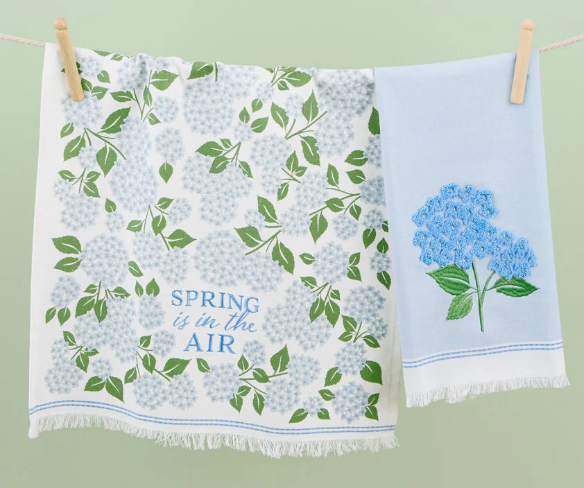 Two-pack towels: blue hydrangea floral print and light blue embroidered design. Available in standard kitchen towel size.