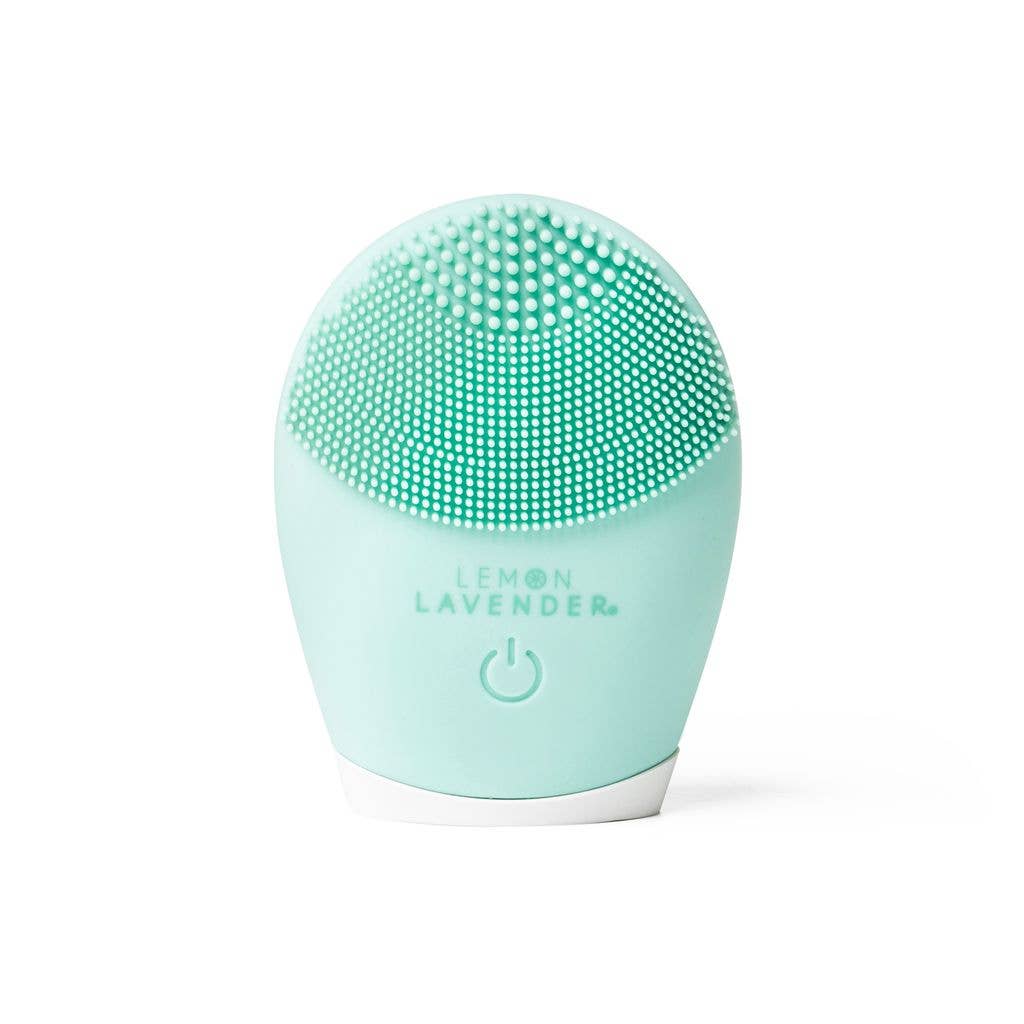 Light green, oval cleanser brush with soft silicone bristles, lit power button, "Lemon Lavender" text. Sizes: not specified.