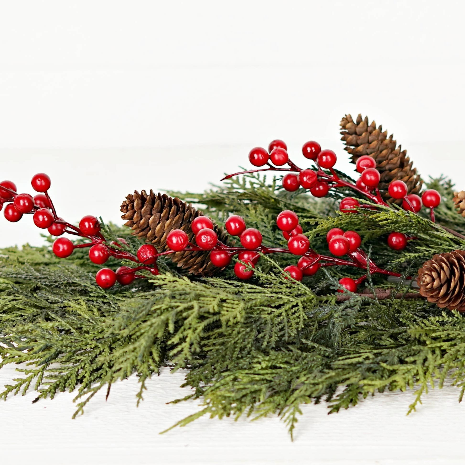 510053- 26inLx16inW Teardrop-Superior Real Touch Mix Cedar features lush green pine branches, natural brown pinecones, and red berry accents crafted from real touch cedar.