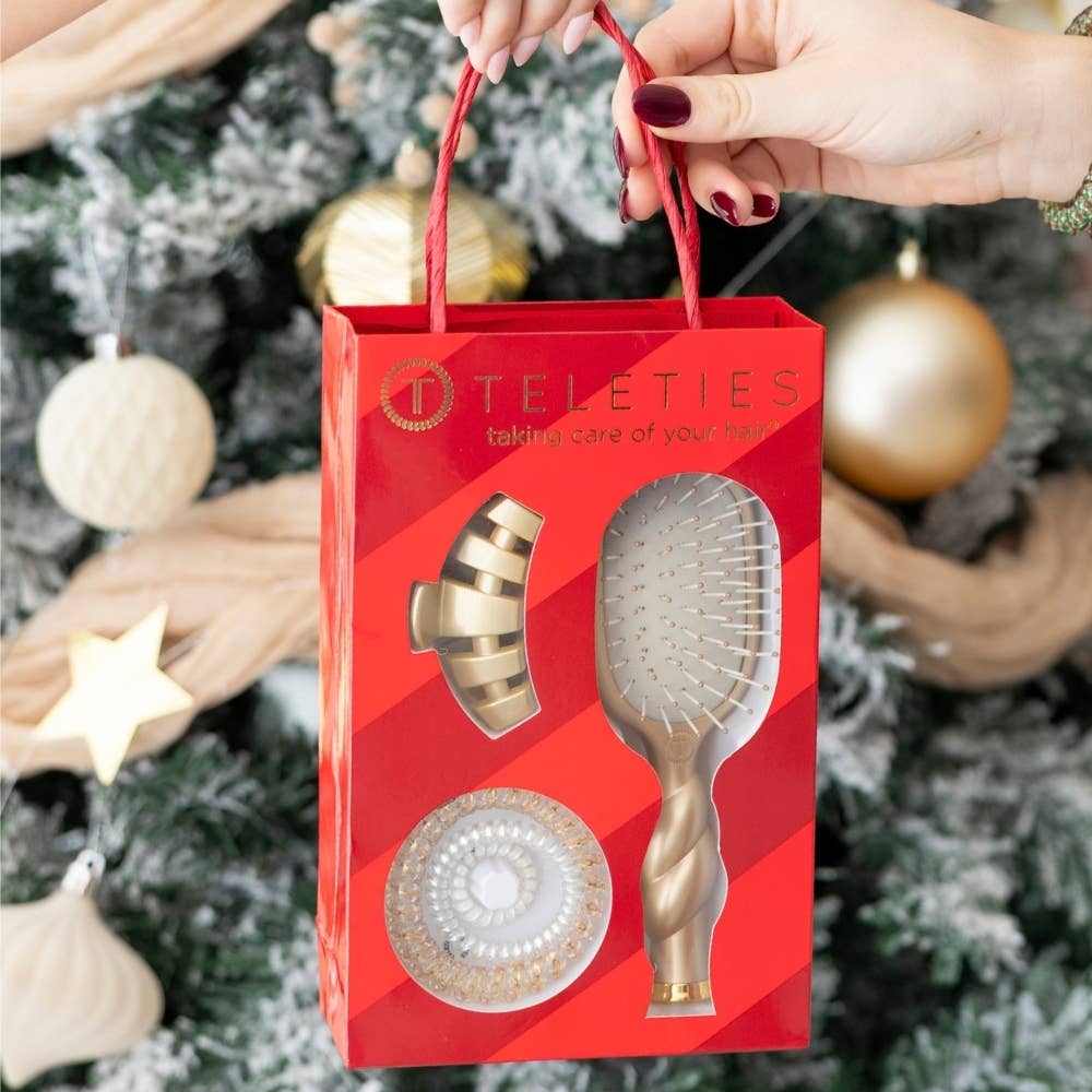 Red Holiday Brush Gift Set containing a gold hairbrush, gold hair clip, and round gold hair accessory.