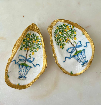 Two white oyster shell jewelry dishes, hand-painted with blue vases and lemon trees, gold edges. Sizes: small, medium.